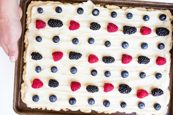 red, white, and blue dessert of sugar cookie bars with white frosting and red and blue berries