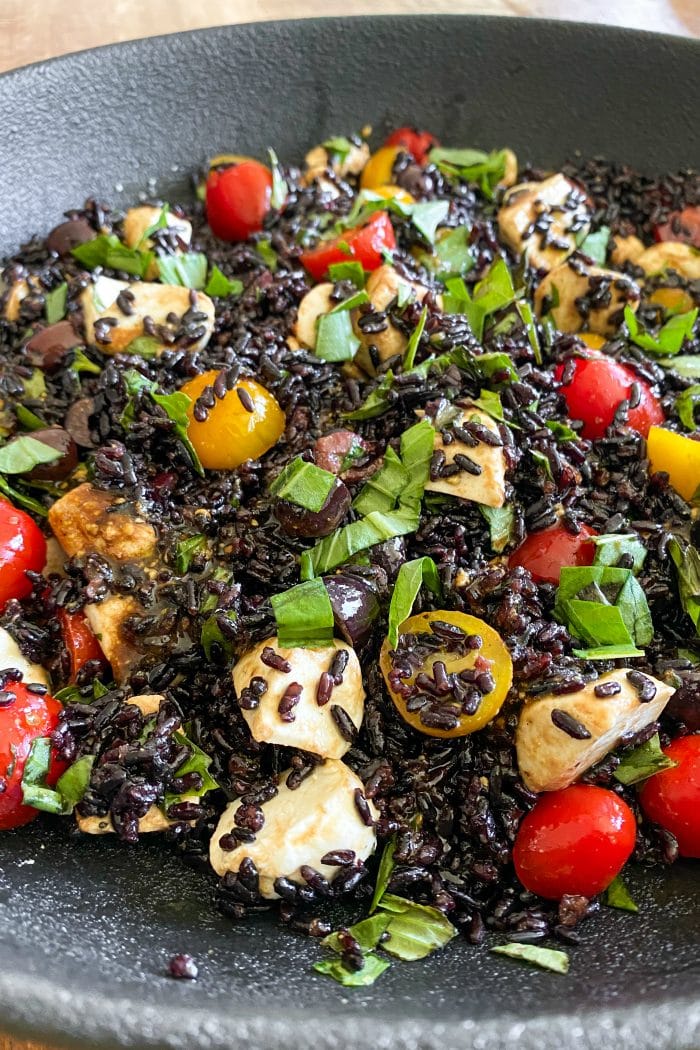 close up forbidden (black rice) salad with cherry tomatoes and mozzarella cheese balls