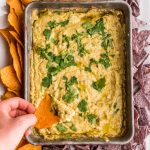 a sweet potato chip dipped into Corn Queso Dip recipe