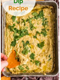 dipping a sweet potato corn chip into oa pan of baked Corn Queso Dip