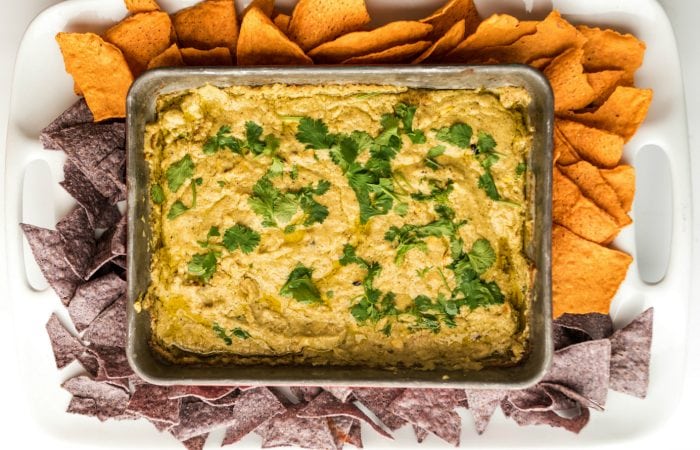 a rectangular pan of Corn Queso Dip Recipe with corn chips around the outside