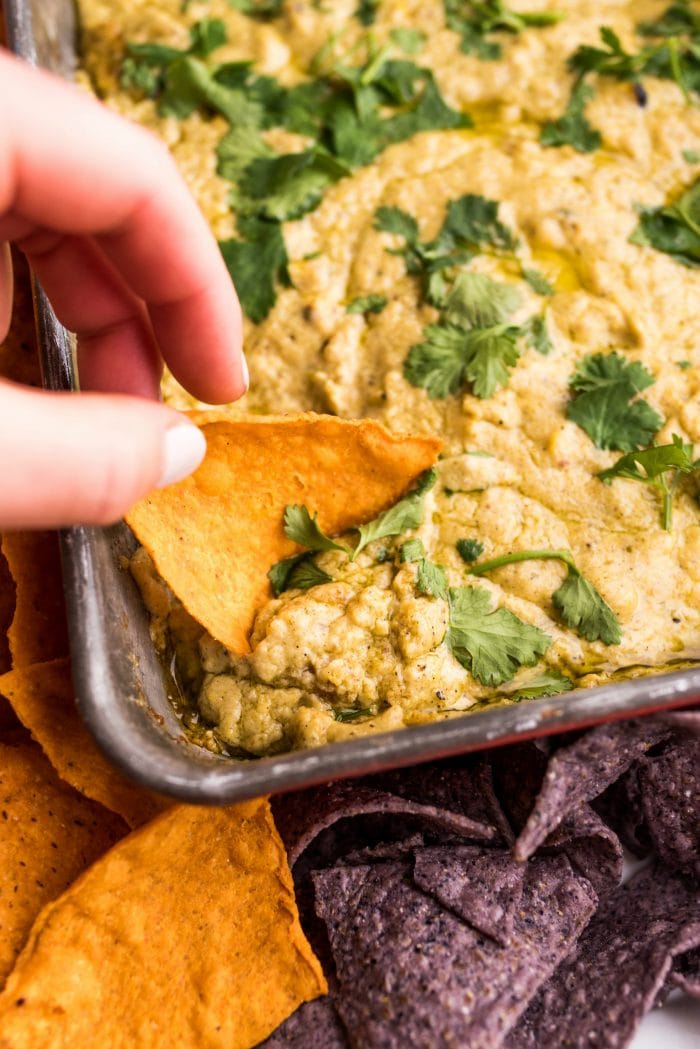 dipping a chip into Corn Queso Dip