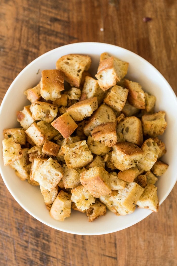 a white, round bowl of homemade croutons