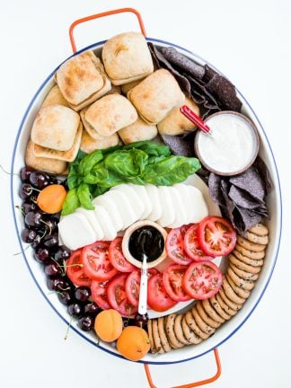 an oval board filled with caprese sandwich ingredients