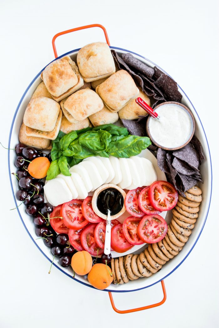 an oval board filled with caprese sandwich ingredients