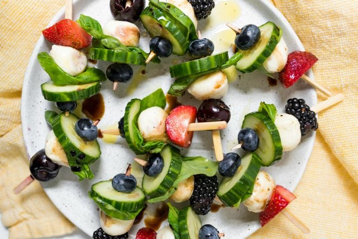 plate of Summer Cucumber Bites on a Stick with berries and cherries