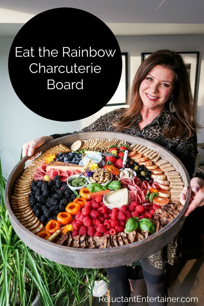 woman holding a round charcuterie board with colorful foods