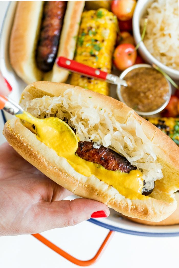 a close up bratwurst with sauerkraut and yellow mustard