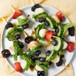 round plate of Summer Cucumber Bites on a Stick drizzled with balsamic glaze