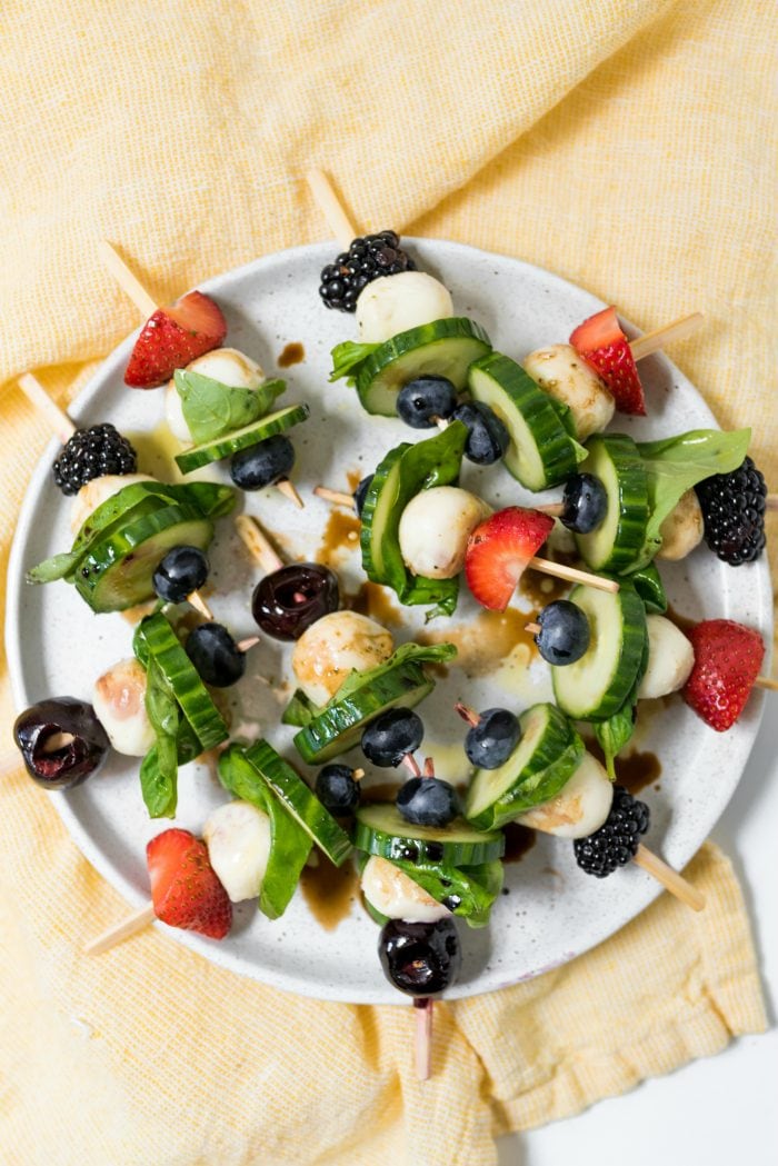 round plate of Summer Cucumber Bites on a Stick drizzled with balsamic glaze