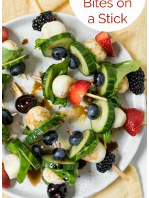 A plate of Summer Cucumber Bites on a Stick with strawberries, cherries, blackberries, and blueberries