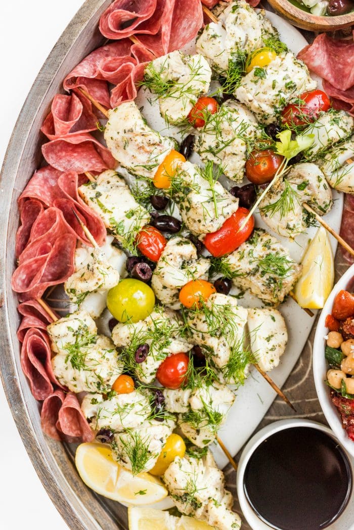 a platter of fish kebabs and cherry tomatoes