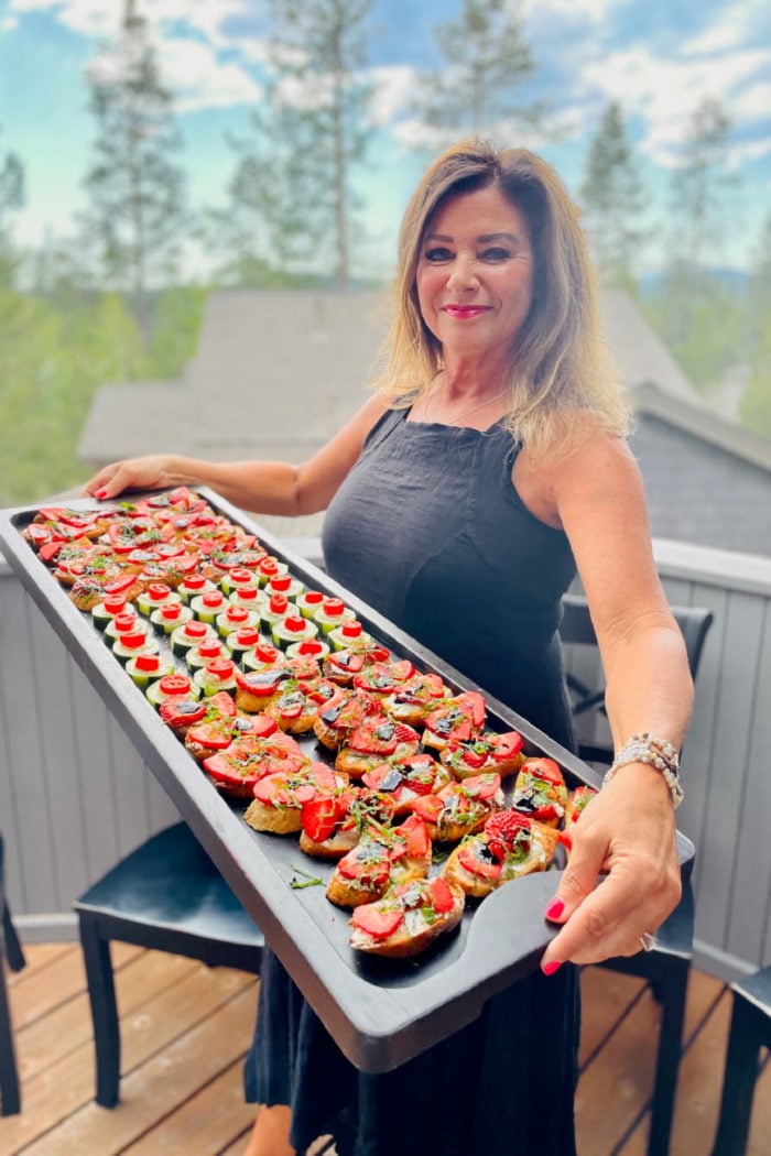 woman holding a board of goat cheese bruschetta