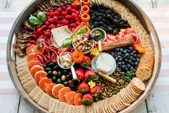 a round board filled with charcuterie and cheese foods