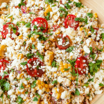 a serving bowl of summer corn tomatoe salad garnished with cilantro