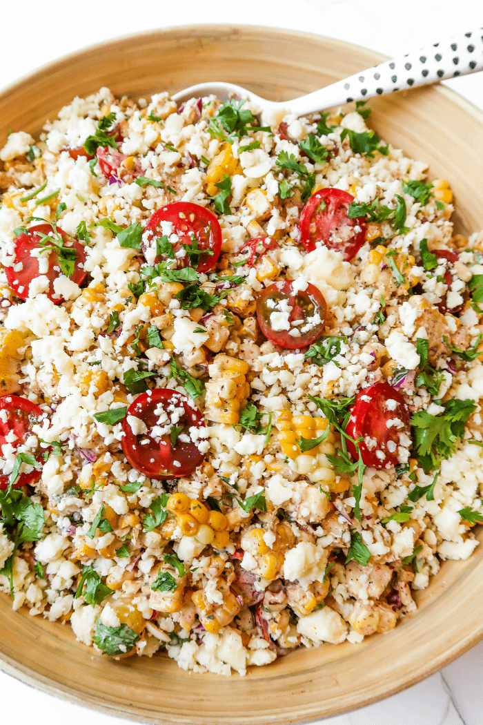 a serving bowl of summer corn tomatoe salad garnished with cilantro