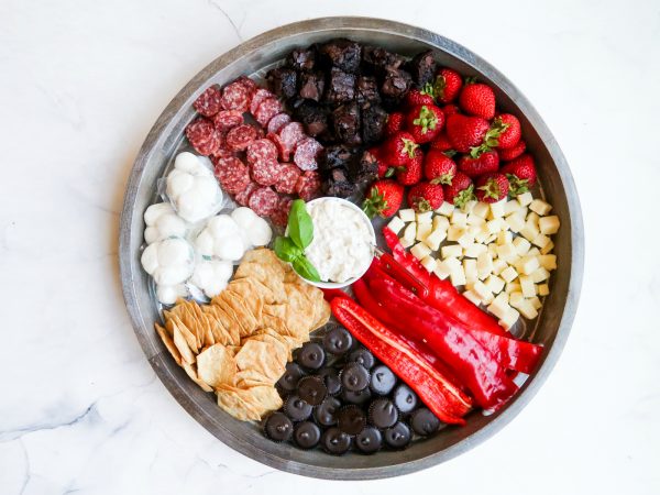 round snack board with a round bowl of cauliflower dip