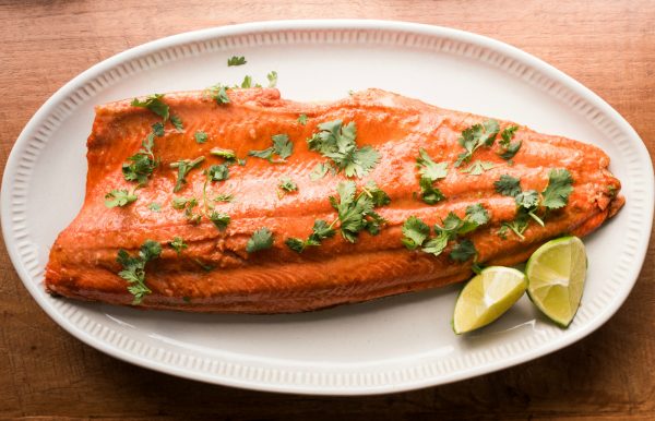 one wild alaskan salmon filet on a plate, garnished with lime