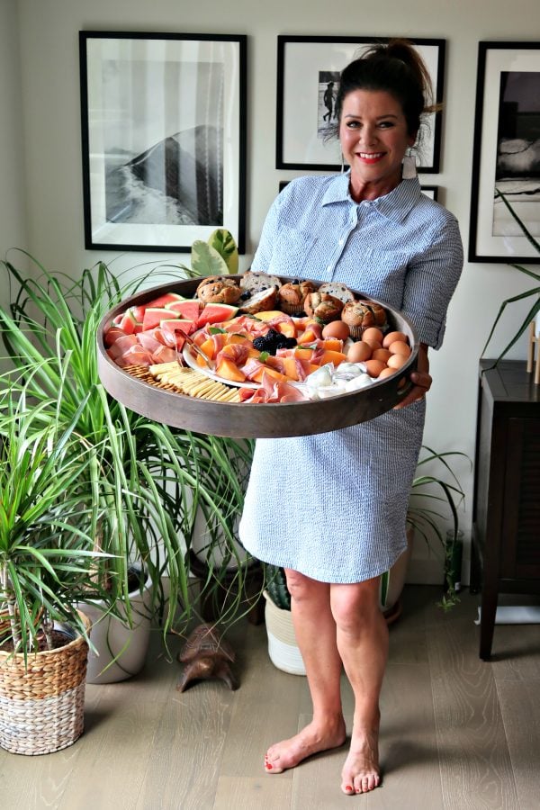 woman holding a round wood Ham Cheese Brunch Board with fresh food