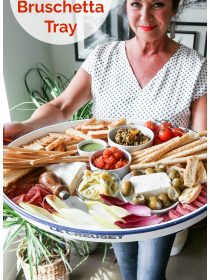 woman holding a tray with bruschetta, cheese, and crackers