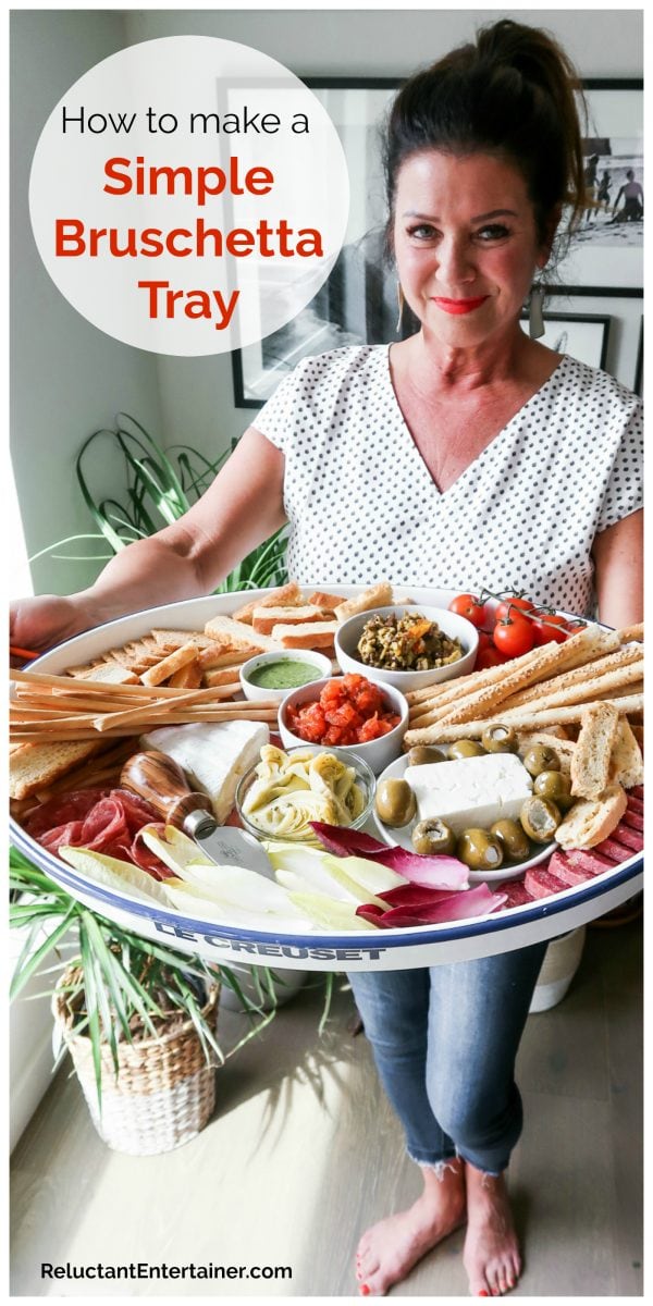 woman holding a tray with bruschetta, cheese, and crackers
