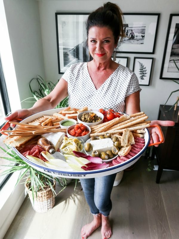 woman holding a Bruschetta Tray with crackers, cheese, and salami