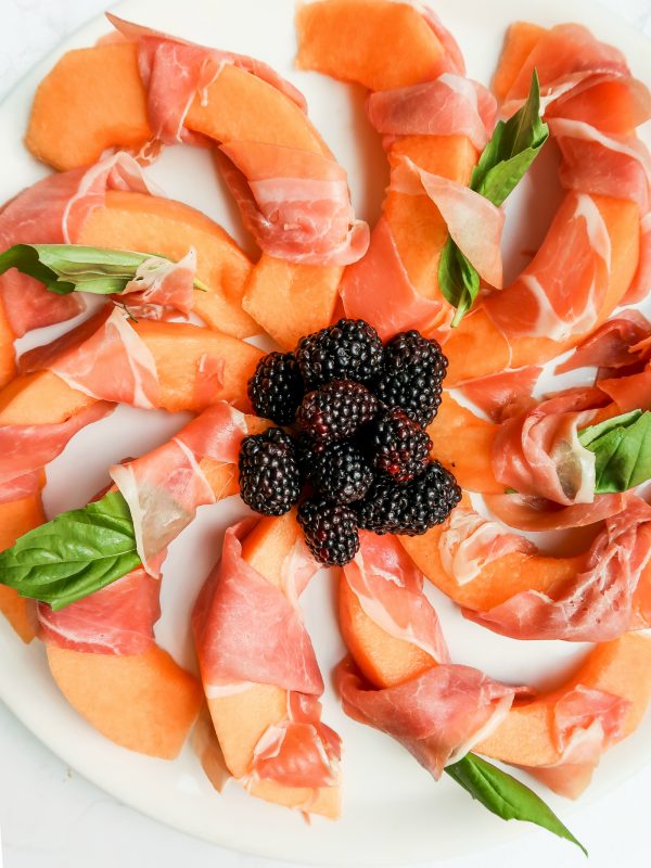 plate of Prosciutto-Wrapped Melon slices with berries in the center