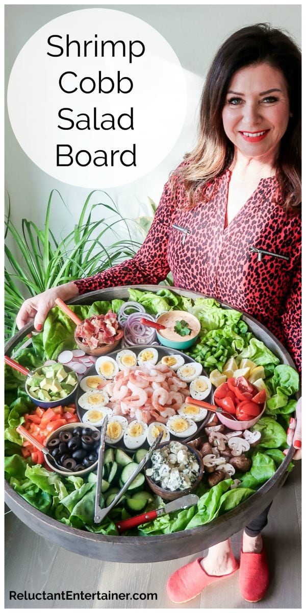woman in red blouse holding a big red board filled with shrimp salad ingredients