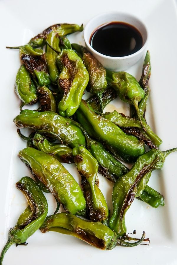 a plate of Shishito Peppers with dipping sauce