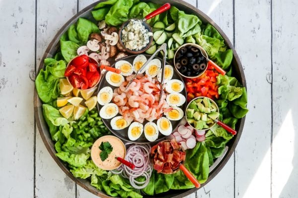 big board with lettuce on the outside, and shrimp cobb salad ingredients