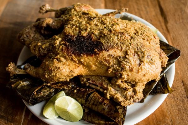 a wholel roasted/grilled duck served on a platter with lime slices