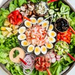 shrimp cobb salad ingredients on a big round board