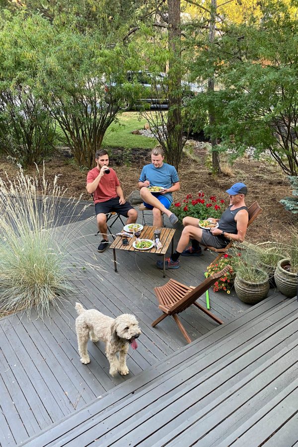 3 people and a dog eating on front deck in summer