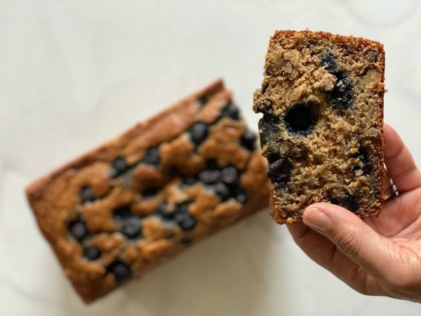 close up, a hand holding a slice of banana blueberry bread