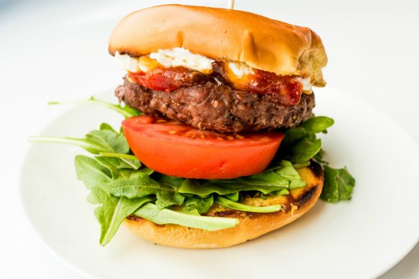 beautiful burger with goat cheese, arugula, bacon jam, and tomato