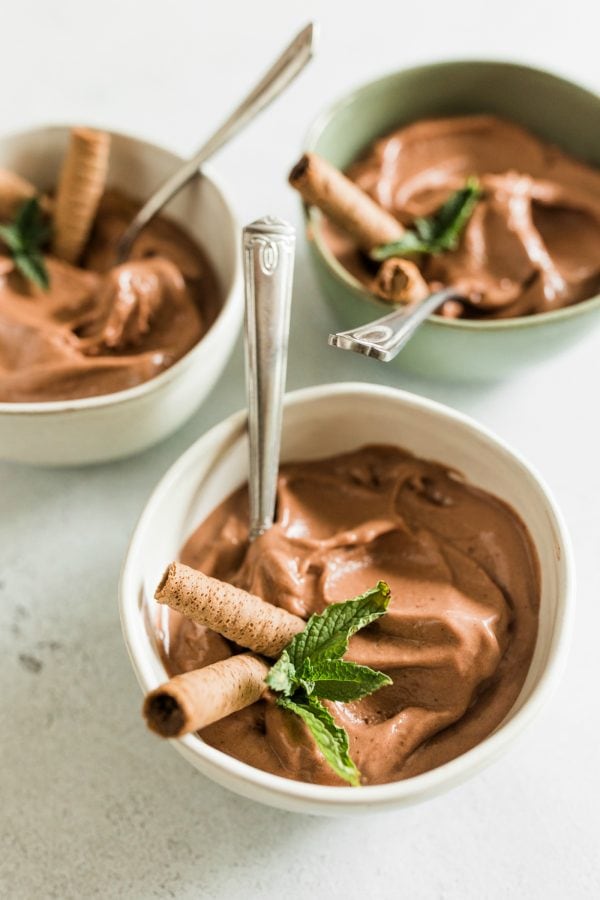 white bowl of banana chocolate peanut butter ice cream with cookie and mint garnish