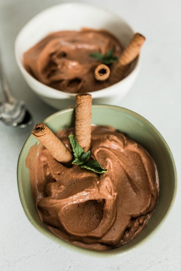 green bowl of chocolate peanut butter ice cream with banana, garnished with cookies