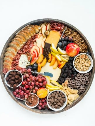 a round fall charcuterie board with cheese, crackers, meat, and fruit