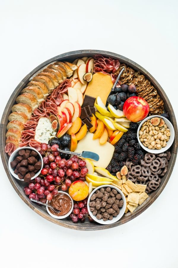 a round fall charcuterie board with cheese, crackers, meat, and fruit