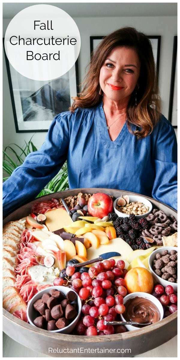 woman in a blue blouse holding a big round fall charcuterie board