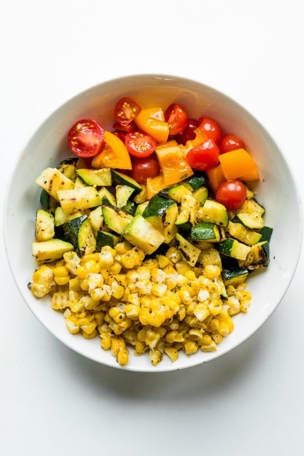 deconstructed corn, zucchini, tomatoes, in a large white bowl
