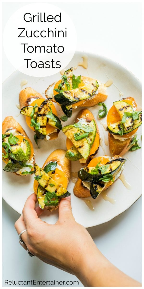 holding a grilled zucchini toast with fresh herbs