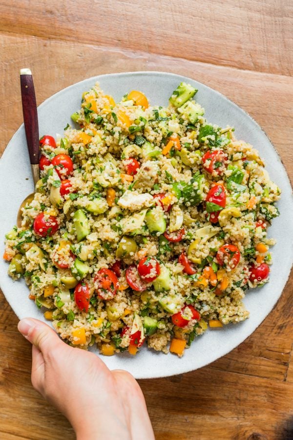 holding a serving plate of Herbed Quinoa Veggie Salad