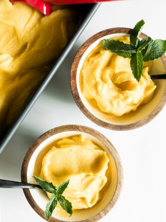 loaf pan of mango coconut sorbet with 2 bowls dish up, with spoons