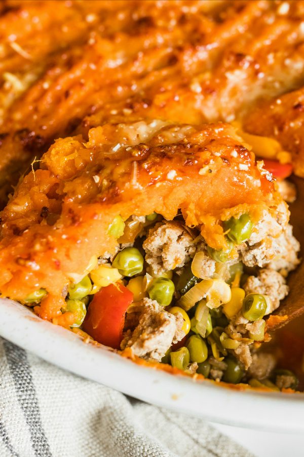 close up Shepherd's Pie filling with meat, peas, and veggies and sweet potato topping