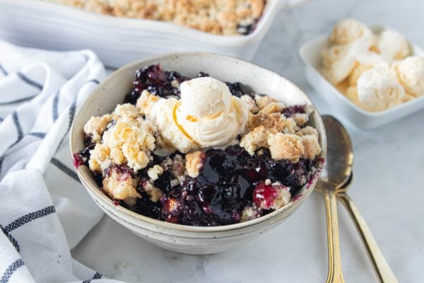 a round bowl of blueberry crunch with a scoop of ice cream