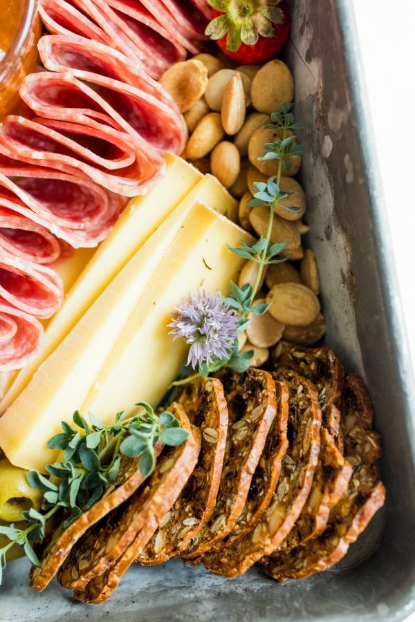 salami, cheese slices, crackers, nuts in a pan