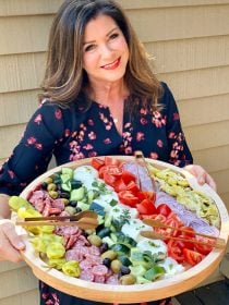 woman holding a round wood tray with deconstructed burrata choopped salad