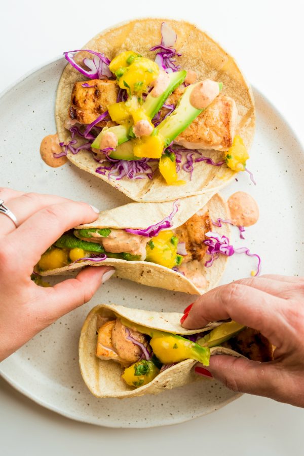 2 hands holding mahi mahi tacos