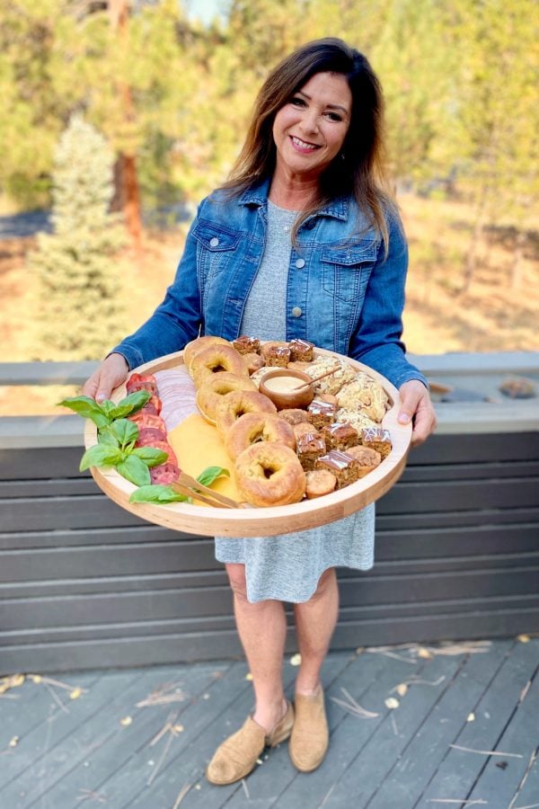 woman holding a round tray filled with pumpkin bagels and sandwich ingredients